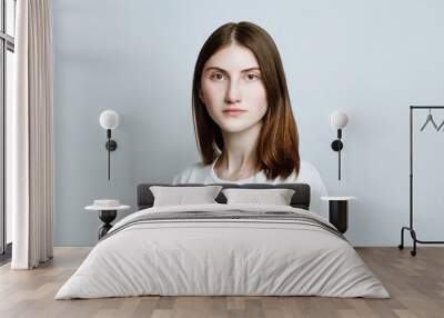 Model portrait without make-up in a white t-shirt on a white background. The girl poses in studio, looking at camera with serious or pensive expression. close up Wall mural