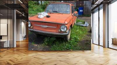 At the scrap metal reception point there is an old broken red Zaporozhets (ZAZ).  Wall mural