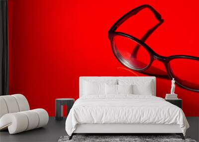 black framed spectacles close up on red background Wall mural