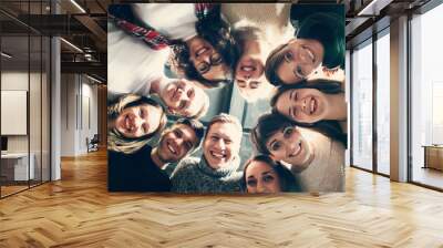 happy friends lying together in circle looking at camera, keeping hands and smiling while lying on w Wall mural