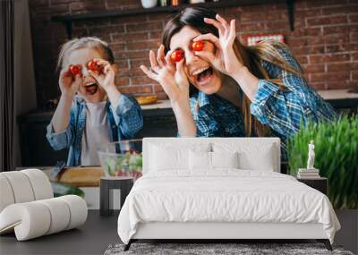 Mother cook with daughter on kitchen,take fun with tomatoes. Wall mural