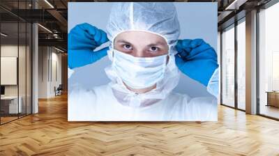 a man in a protective suit, gloves and puts a mask on his face. The concept of health care. Wall mural