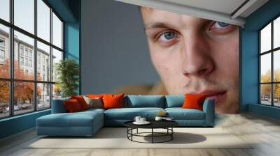 Close-up of a young Eastern European man with a neutral expression, looking at the camera Wall mural