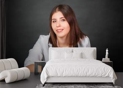 Portrait of an attractive woman photographer sitting on a chair with a camera in her hands in the studio on a gray background. Wall mural