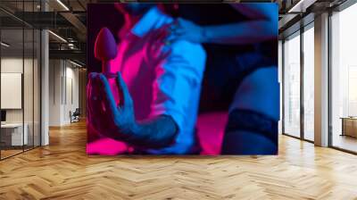 A couple of lovers use an anal plug in the bedroom in neon light. Wall mural