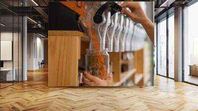 A man fills a jar with red lentils. Selling bulk goods by weight in an eco store. Trade concept without plastic packaging Wall mural