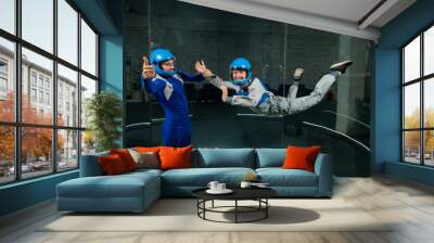 A man teaches a woman how to fly in a wind tunnel. Free fall simulator. Wall mural