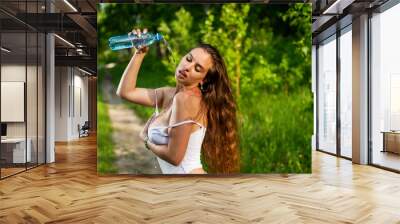 Beautiful caucasian woman sprays herself with water for freshness on a hot summer day. Wall mural