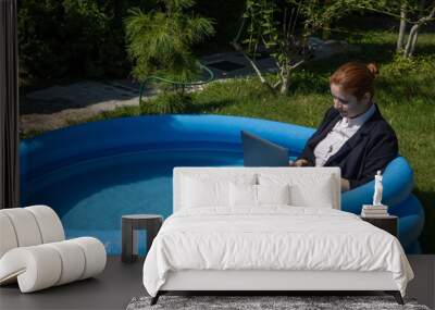 Caucasian business woman working on laptop while sitting in swimming pool.  Wall mural