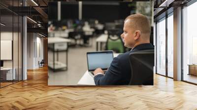 Caucasian deaf man typing on laptop in office.  Wall mural