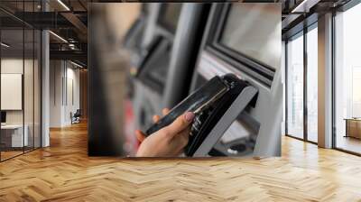 Close-up of a woman paying at a self-service machine using a contactless phone payment Wall mural