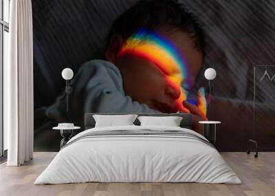 Close-up portrait of a newborn boy with a prism beam on his face. Rainbow. Wall mural