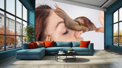 Closeup of a Caucasian woman holding a large snail. The use of shellfish in cosmetology. Wall mural