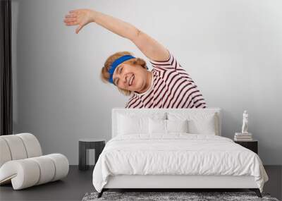 Elderly woman doing fitness doing side bends on a white background. Wall mural