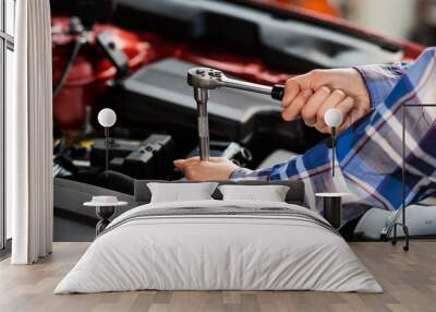 Female auto mechanic unscrewing a nut to replace a car spark plug. Wall mural