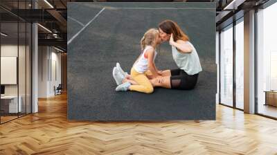 Mother and daughter go in for sports outdoors. Caucasian woman and little girl are engaged in fitness at the stadium. Wall mural