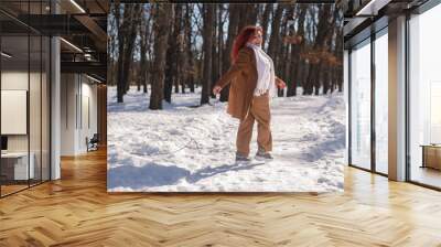 Portrait of an excited red-haired curly fat woman in the park in winter. Wall mural