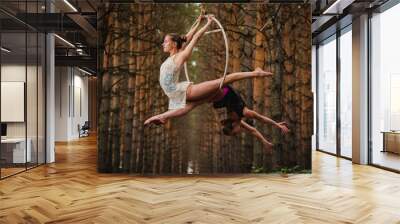 two beautiful and slim gymnasts doing difficult exercises on aerial silk in the forest two beautiful Wall mural