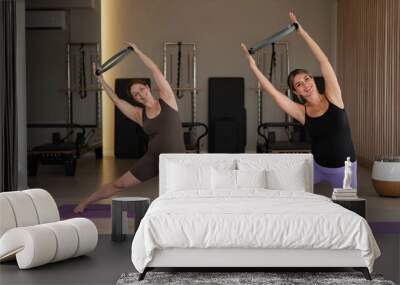 Two pregnant women doing yoga. Exercises with a gymnastic circle for Pilates.  Wall mural