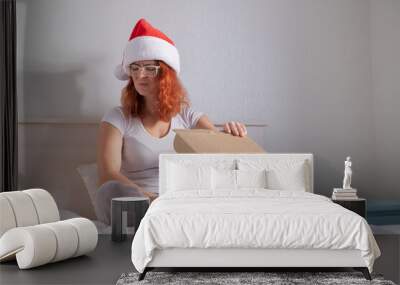 Upset woman in santa claus hat unpacks online purchase. The girl received the wrong parcel. Wall mural