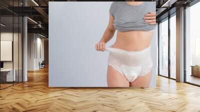 Woman in adult diapers on a white background. Incontinence problem. Wall mural