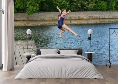 Caucasian girl jumping in remote lake Wall mural