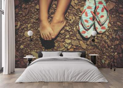 slippers flip flops and children's feet on a stone beach Wall mural