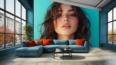 A beautiful young Millennial woman with thick hair. Turquoise background. Wall mural