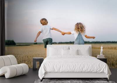 Happy and free people, children run through the beveled field of wheat, people from behind Wall mural