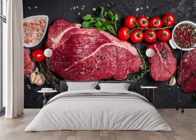 Assortment of raw cuts of raw beef meat steaks with spices on a dark background. Long banner format. top view Wall mural