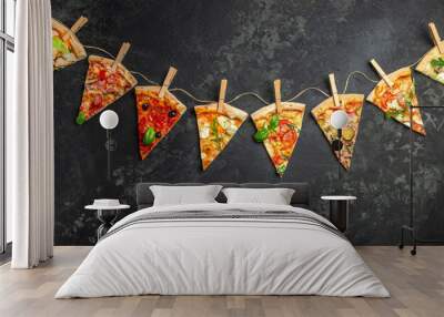 Different pieces of pizza on a string with clothespins dark background. Long banner format. top view Wall mural