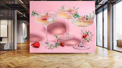 drink cocktail with ice in a glass on pink background. refreshing fruit cocktail or punch with wine champagne, strawberries, ice and rosemary Wall mural