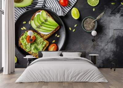 Healthy avocado toasts for breakfast or lunch with rye bread, cream cheese, arugula, sliced avocado, pumpkin, hemp and sesame seeds, salt and pepper. Vegetarian food concept. Clean eating. Top view Wall mural