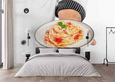 professional chef holding plate with tasty pasta Dish with tomato sauce and basil isolated on white background Wall mural