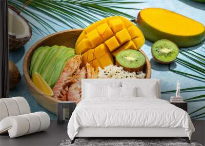 tropical bowl with avocado, prawns, rice, mango, kiwi and coconut, tropical food on the sea beach on light background with tropical leaves. Healthy food, clean eating, Buddha bowl, top view Wall mural