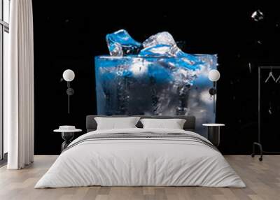 cold water with ice in a blue glass on a black background Wall mural