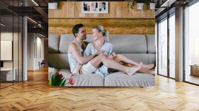 Lovely couple together at home. Pretty woman and attractive man stylish casual clothes sitting on a sofa hugging Wall mural