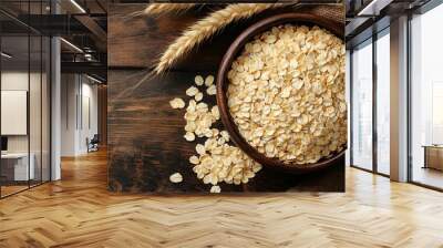 oat flakes in bowl and ears on wooden table top view. Uncooked oatmeal Wall mural