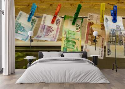 Russian paper banknotes of fifty, one hundred, two hundred, five hundred and one thousand rubles are attached with a clothespin to a clothesline for drying clothes Wall mural