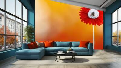 A vibrant red flower with a bee perched on it against a blurred orange background during daylight Wall mural