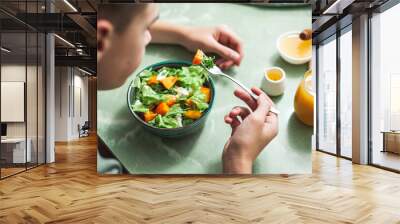 Vegan breakfast or lunch. Teen boy eating breakfast Winter vitamin salad on white table with a green napkin Diet food. Selective focus  Wall mural