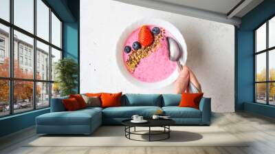 Woman's hand holding spoon in the Smoothie bowl with fresh berries, golden and brown flax seeds. Healthy breakfast, fitness, diet concept. Wall mural