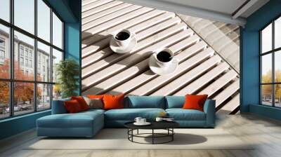 Two cups of black coffee, on a light wood table. View from above. Wall mural