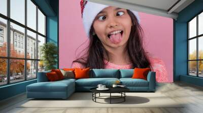 Portrait of  funny emotion girl in red santa claus hat isolated on pink background. Beautiful girl looking happy and excited. Happy Christmas and New Year  holidays full of fun. portrait copy space Wall mural