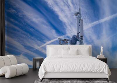 Uniformed worker repairing cell tower against sky Wall mural