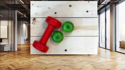 two red dumbbells along with two green apples on white wooden background. Copy space. concept Wall mural