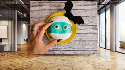 Decorated doughnut on Halloween, blue color with paper bats, a hand reaches out for food Wall mural