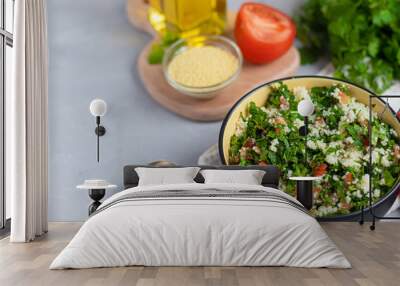 Tabbouleh  salad in a round plate on a light gray background under concrete. Wall mural