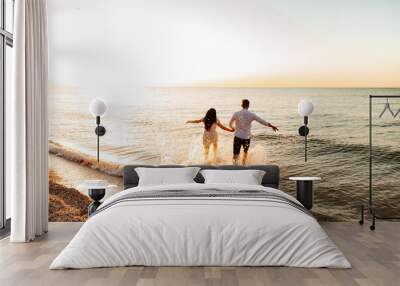 Loving couple in white clothes during a honeymoon at sea walk on the sand at a photoshoot Love Story, ocean coast, beach Wall mural