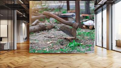 a large ax is driven into a stump in the street. sun glare. firewood on the background. Wall mural